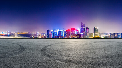 Race track road and modern city skyline with buildings in Hangzhou at night.