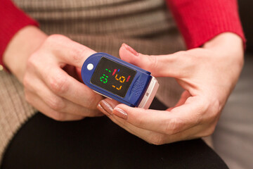 Woman measuring her blood oxygen level while sitting sofa at home.