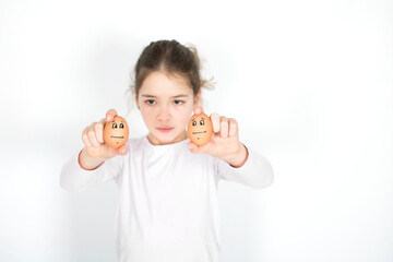 Young girl show two eggs with sad face isolated on white background. Easter and social distance concept.