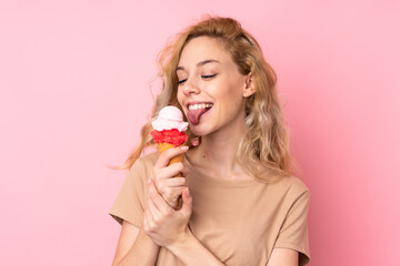 Young blonde woman holding a cornet ice cream isolated on pink background