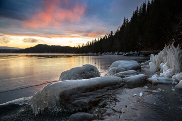 Icy frozen shore of the lake in sunset time.