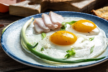 Portion of fried eggs with lard bacon. National Ukrainian or belorussian cuisine. Food recipe background. Close up