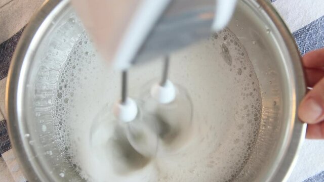 The whipping cream for a vegan cake Esterhazy. Whipping eggs with a mixer close-up. 60 fps.