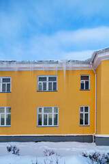 Vintage yellow house and Icicles hang from the roof in winter