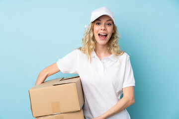 Young delivery woman isolated on blue background with surprise facial expression