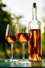 Two glasses of rose wine and a bottle on the table in the vineyard