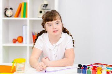 A girl with down syndrome is engaged in creativity in a specialized school. Accessible education for disabled concept