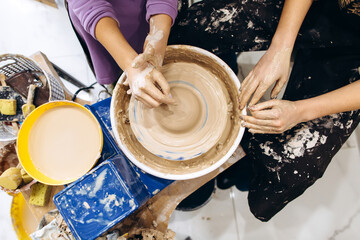 Creative process of creating pottery by mother and daughters. Female hands in a pottery workshop.