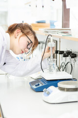 In a chemical laboratory, a girl laboratory assistant drips a solution into a measuring beaker with a special pipette