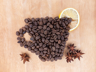 Cup-shaped applique. Coffee beans are laid out on a wooden table with lemon wedge and anise flowers. .Morning cup of coffee with lemon.