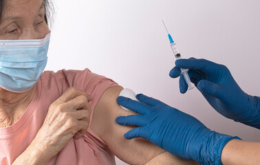 Elderly asian woman is vaccinated against Covid-19 Doctor draws a dose of vaccine into a syringe. Coronavirus vaccination elderly concept. High quality photo