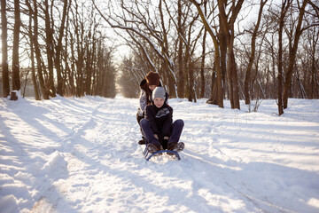 Fototapeta na wymiar Happy boy and girl with sleds in the park in winter. concept of rest on the snow.