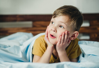 cheerful and surprised child lies on the bed