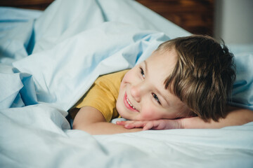 Fototapeta na wymiar cheerful boy lies on blue bedding