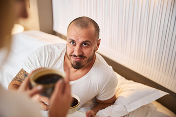 Contented man drinking coffee with his female spouse