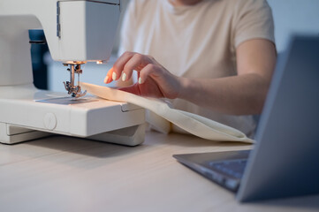 Close-up. A woman works on an electric sewing machine at home