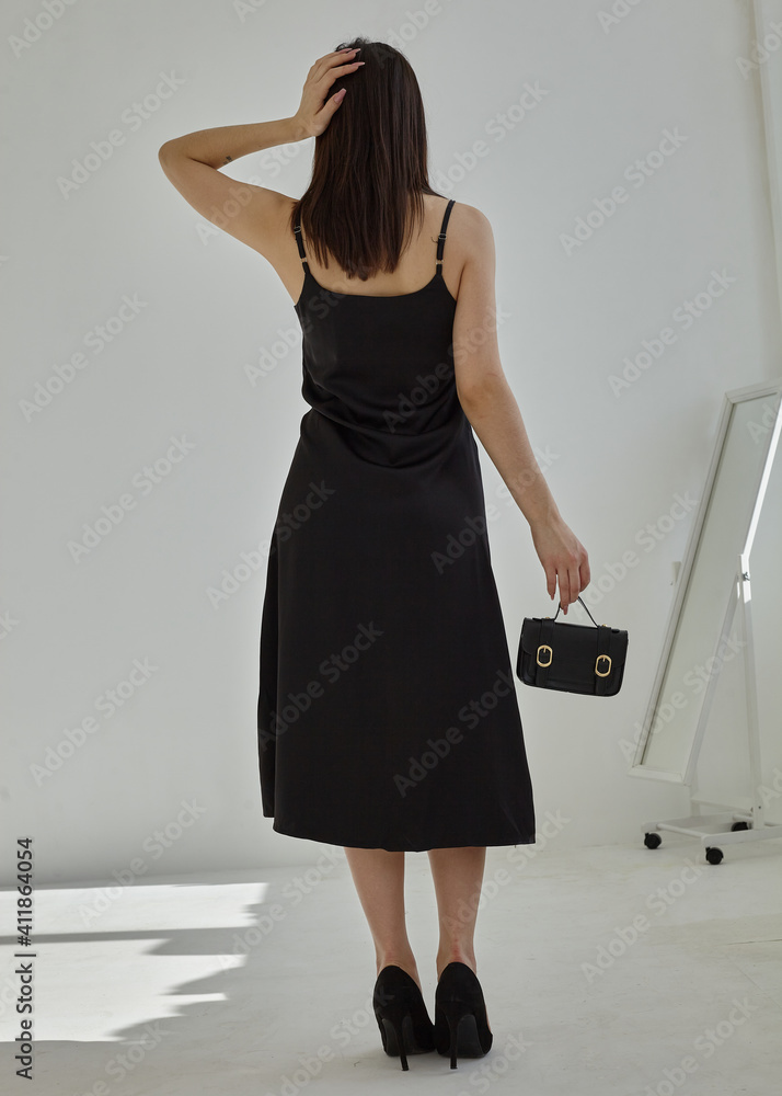 Wall mural beautiful stylish girl stands with her back on a light background