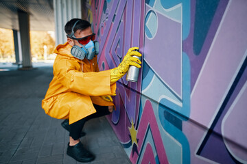 Street artist painting colorful graffiti on wall