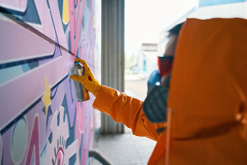 Street artist painting colorful graffiti on wall