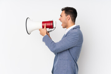 Young handsome businessman on isolated background shouting through a megaphone