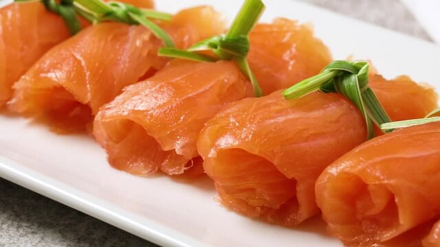 Rolls of smoked salmon and garlic grass as snack