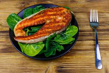 Grilled salmon steak with spinach on wooden table