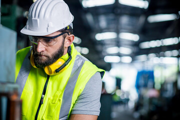 Chief engineer is looking at a work that he is making or checking security system setup at metal lathe industrial manufacturing.