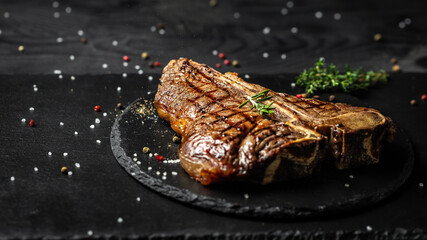 Grilled T-bone or aged wagyu porterhouse grilled beef steak on stone table. Long banner format, top...