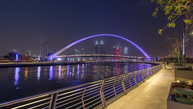 Illuminated Pedestrian Bridge over the Dubai Water Canal day to night transition timelapse which links Dubai Creek to Jumeirah Beach weaving through Deira, Downtown Dubai and Safa Park. Skyscrapers