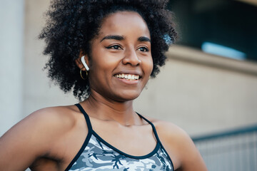 Afro athletic woman standing outdoors.