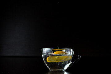 water splashes. freezing motion. frozen alcohol spray. a slice of lemon fell into a cup of water. stopped action. menu design. side view. advertising poster