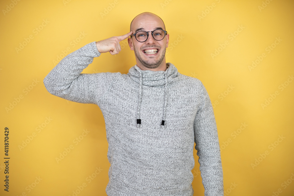 Wall mural young bald man wearing glasses over yellow background having an idea