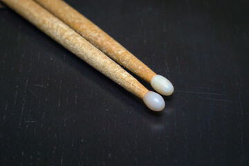 Used wooden drumsticks with white tips on dark background