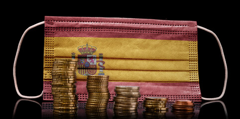 Medical mask with the flag of Spain behind some shrinking stacks of various coins.(series)
