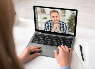 Young woman having online video conference with her boyfriend on laptop computer from home