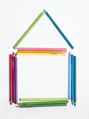 Colored pencils are laid out on a white background in the shape of a house.