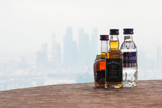 Moscow, Russia - January, 2021: Mini bottles of whiskey Jack Daniels, cognac Courvoisier, vodka Finlandia on the table, view of the misty city from the roof. Moscow business center
