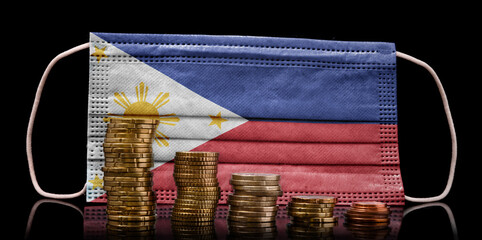 Medical mask with the flag of Philippines behind some shrinking stacks of various coins.(series)