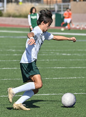 Obraz premium Young Athletic boy kicking the ball during a soccer game