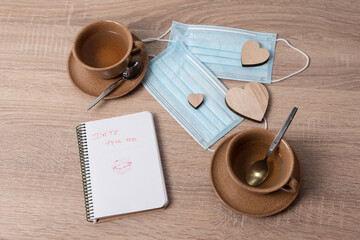 Two tea cups, facemasks and love hearts for 14 february date