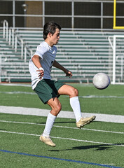 Fototapeta premium Young Athletic boy kicking the ball during a soccer game