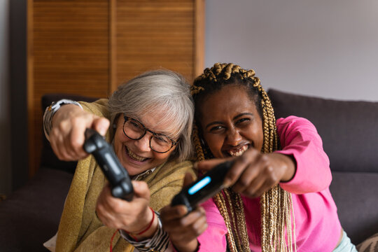 Young african woman next to an older woman competing with a console game