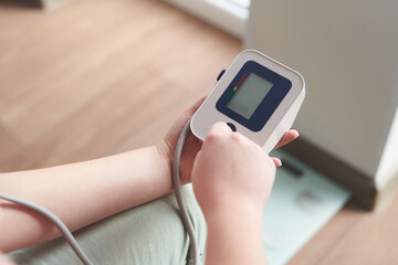 a young girl measures her blood pressure with a tonometer