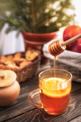 hot tea with lemon and honey on a wooden table background, on a background of cookies and apples in the sunlight