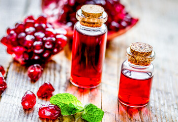 sliced pomegranate and extract in glass on wooden background
