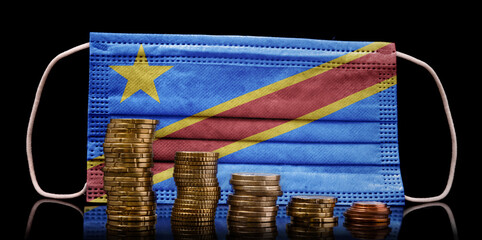 Medical mask with the flag of Democratic Republic of the Congo behind some shrinking stacks of various coins.(series)