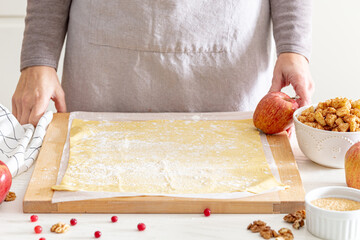 making strudel - dough, apples, cinnamon, nuts, brown sugar. woman preparing apple strudel