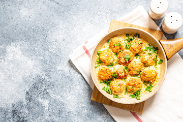 meatballs in white sauce in a frying pan on a gray background, comfortable homemade healthy food