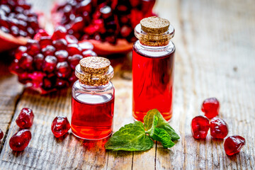 sliced pomegranate and extract in glass on wooden background