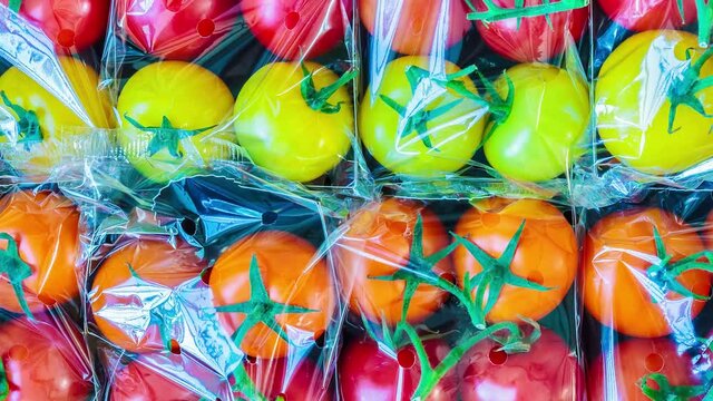 Horizontal pan of a display with fresh plastic wrapped cherry tomatoes